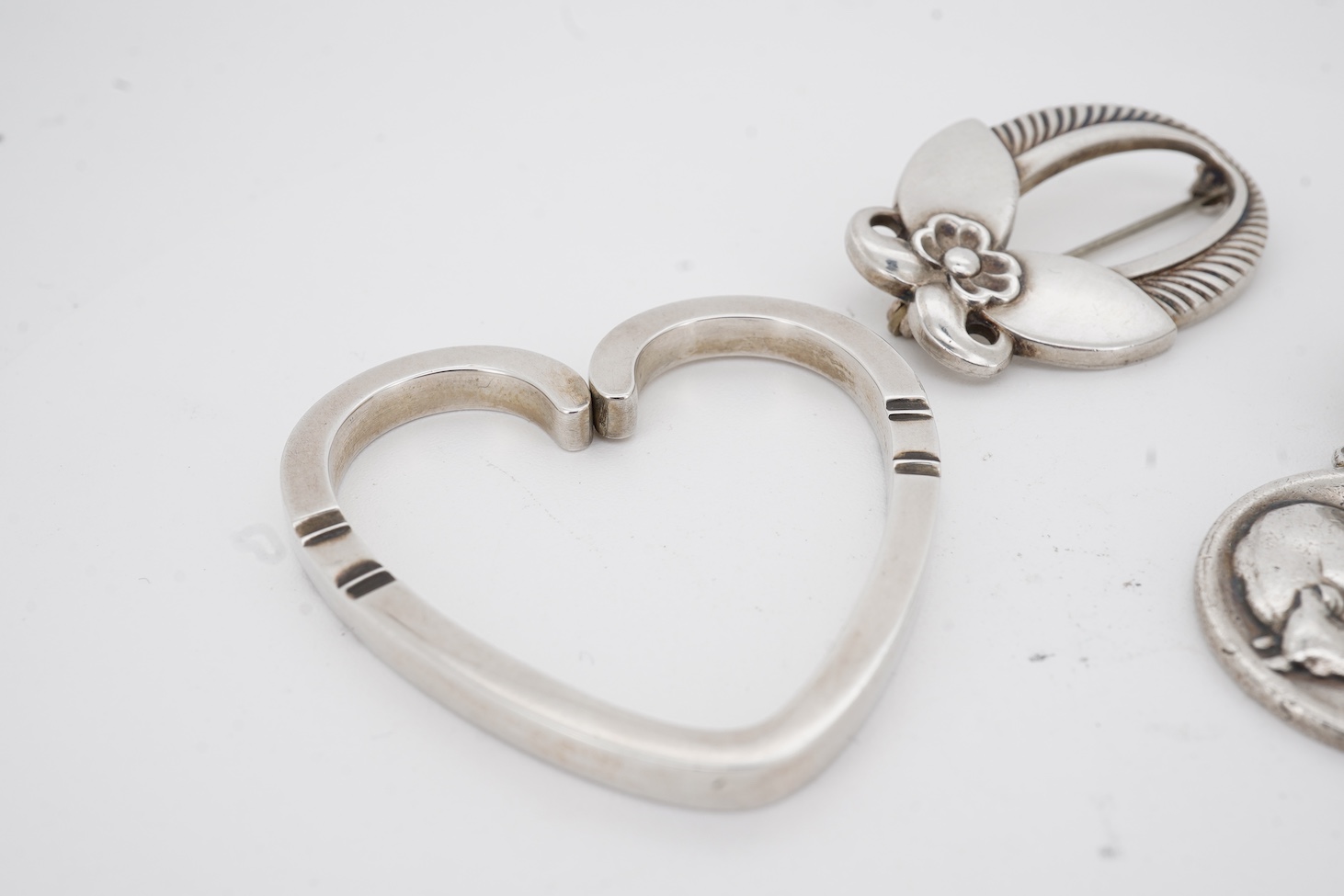A Danish Georg Jensen sterling twin dolphin brooch, 40mm and a similar flower brooch, design numbers 317 and 227, a 1960's Georg Jensen silver bracelet, design no.46 and a similar 1970's silver heart pendant, design no.4